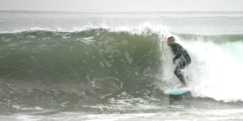 Surfer riding beneath the cover of a breaking wave